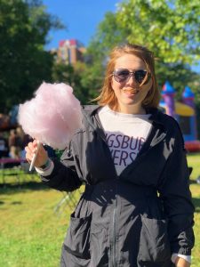 Photo of Lizzy standing outside holding cotton candy and smiling